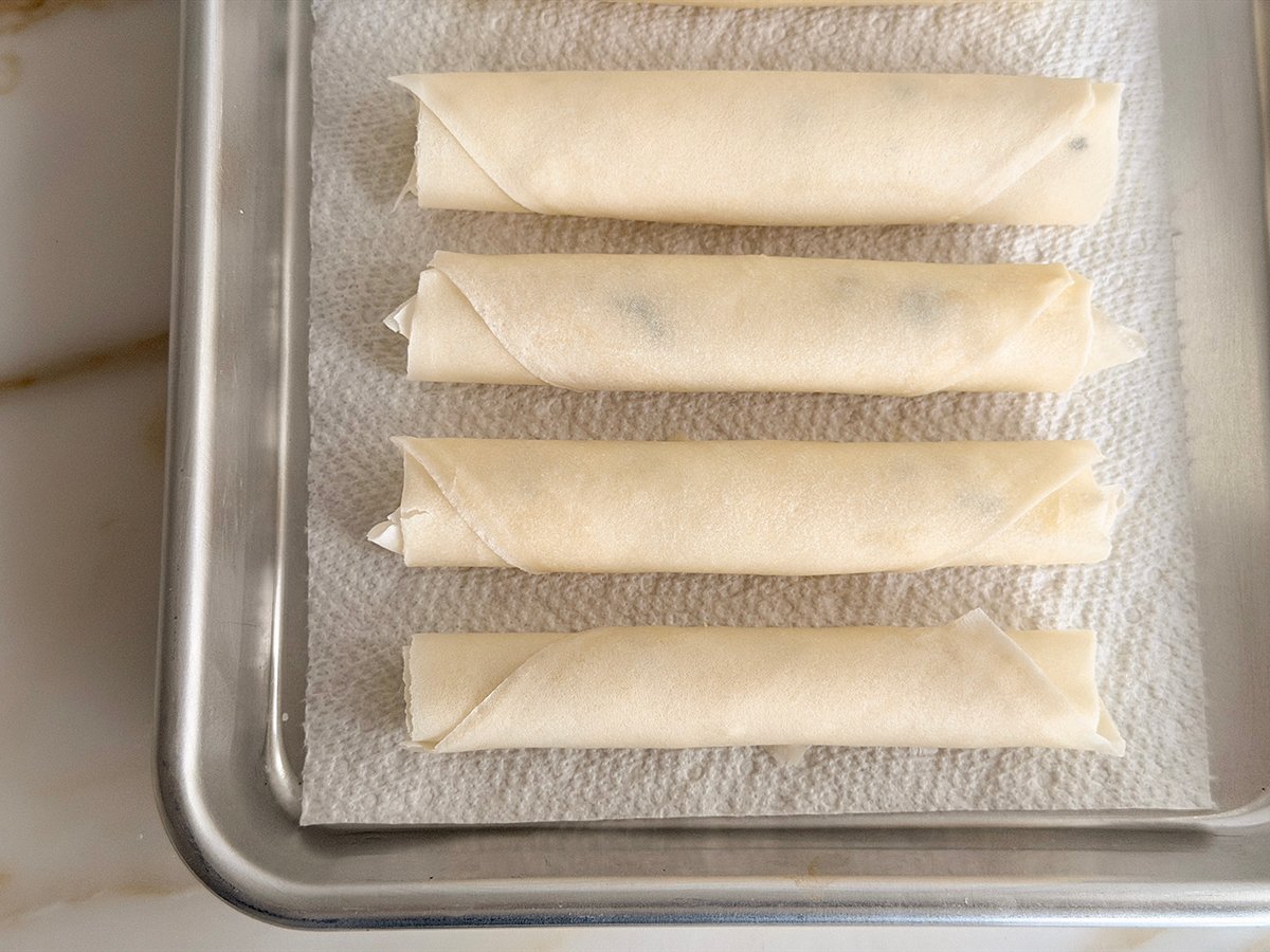 raw cheese rolls on a piece of paper towel on a baking sheet