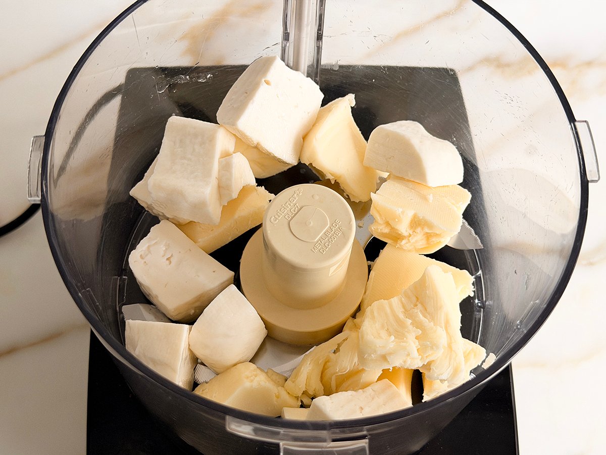 Chunks of white cheese in the bowl of a food processor