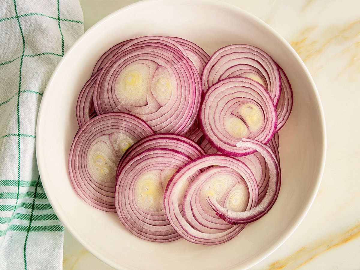 Thinly sliced red onions in a white dish