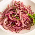 Sumac onions in a white bowl with a mint sprig on the side