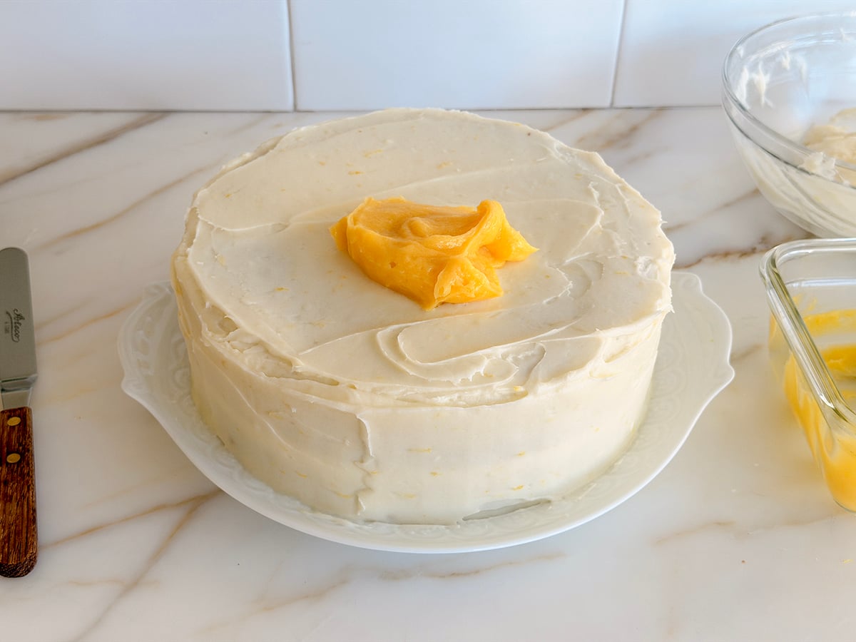 Dollop of lemon curd on a white frosted cake
