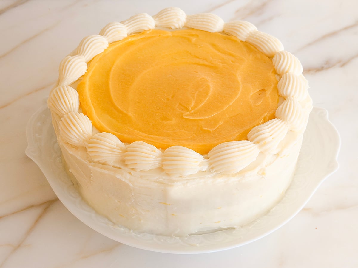 Lemon cake with lemon curd on top and a piped shell border