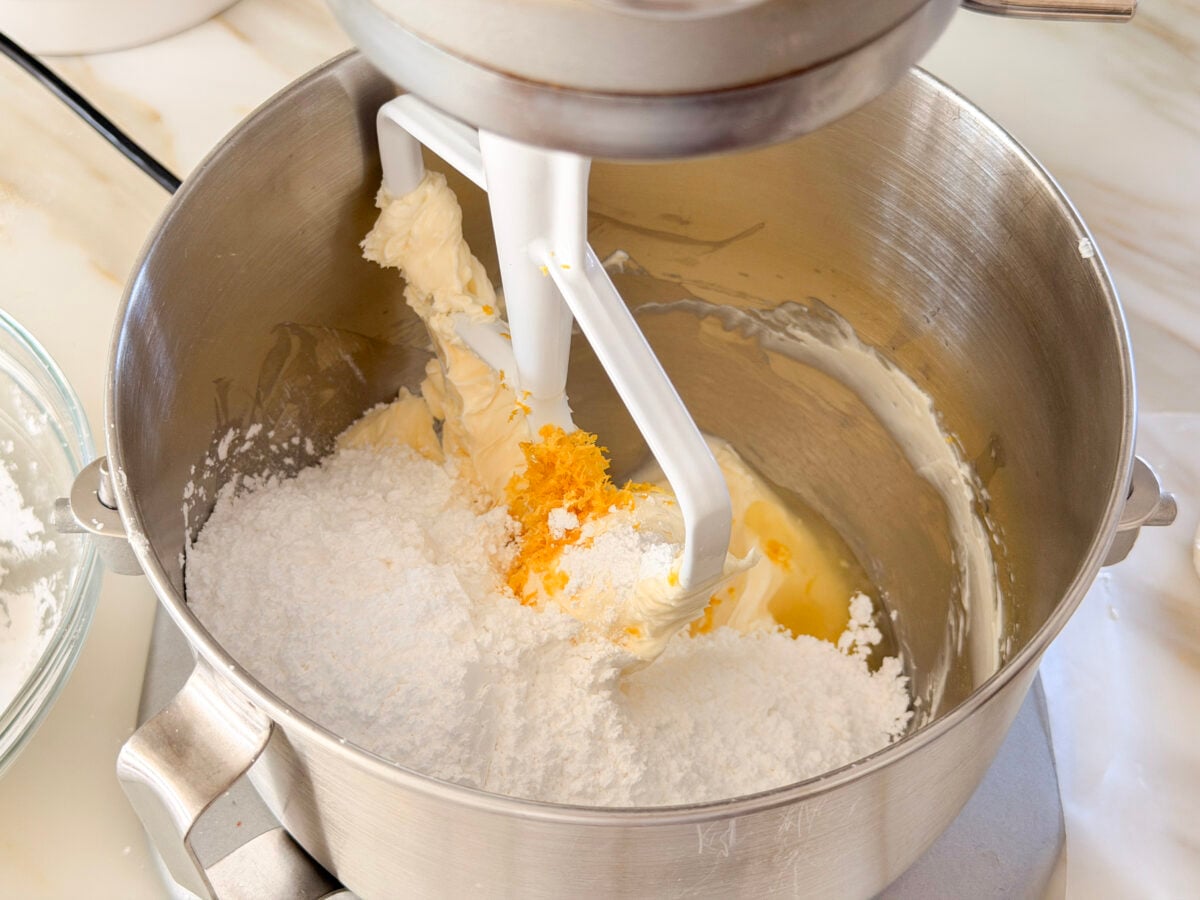 Confectioners' sugar and lemon zest in the bowl of a stand mixer with butter and cream cheese