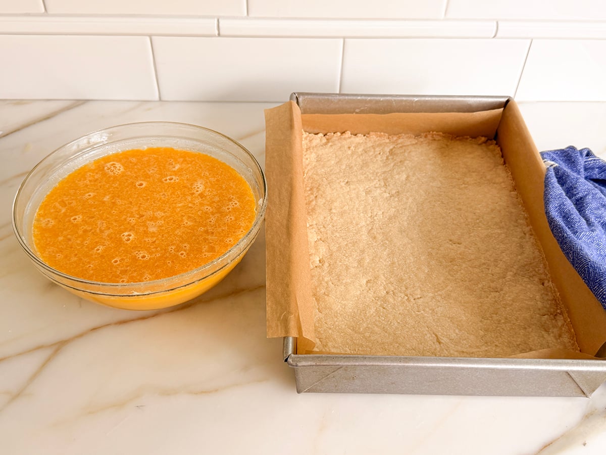 Baked crust in a pan beside a glass bowl of egg custard