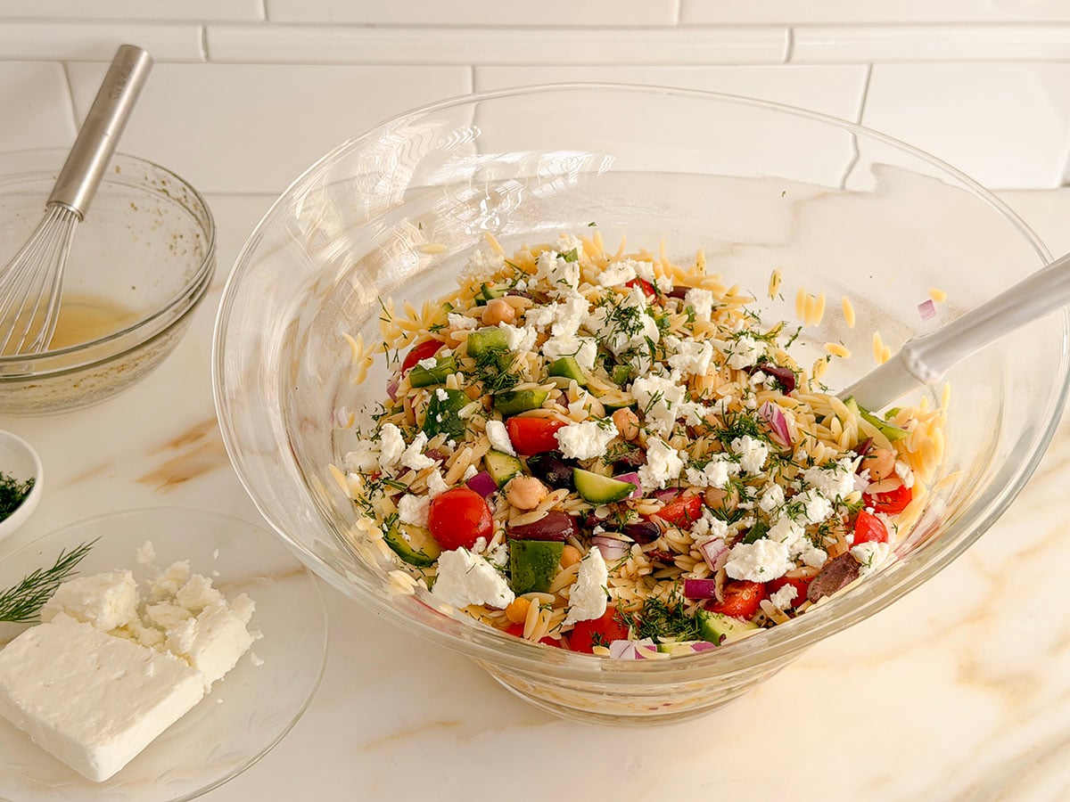 Pasta salad in a glass bowl with feta on the side