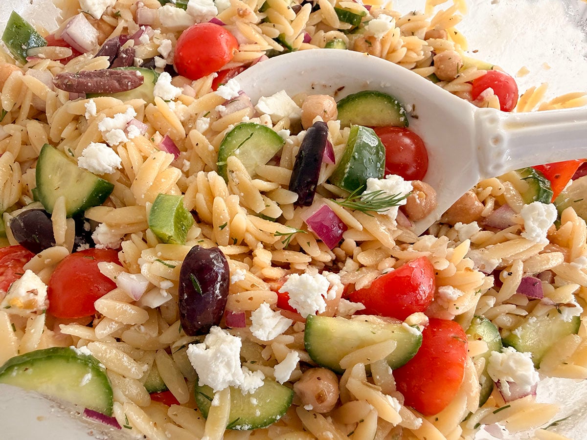 Orzo salad with veggies in a white spoon