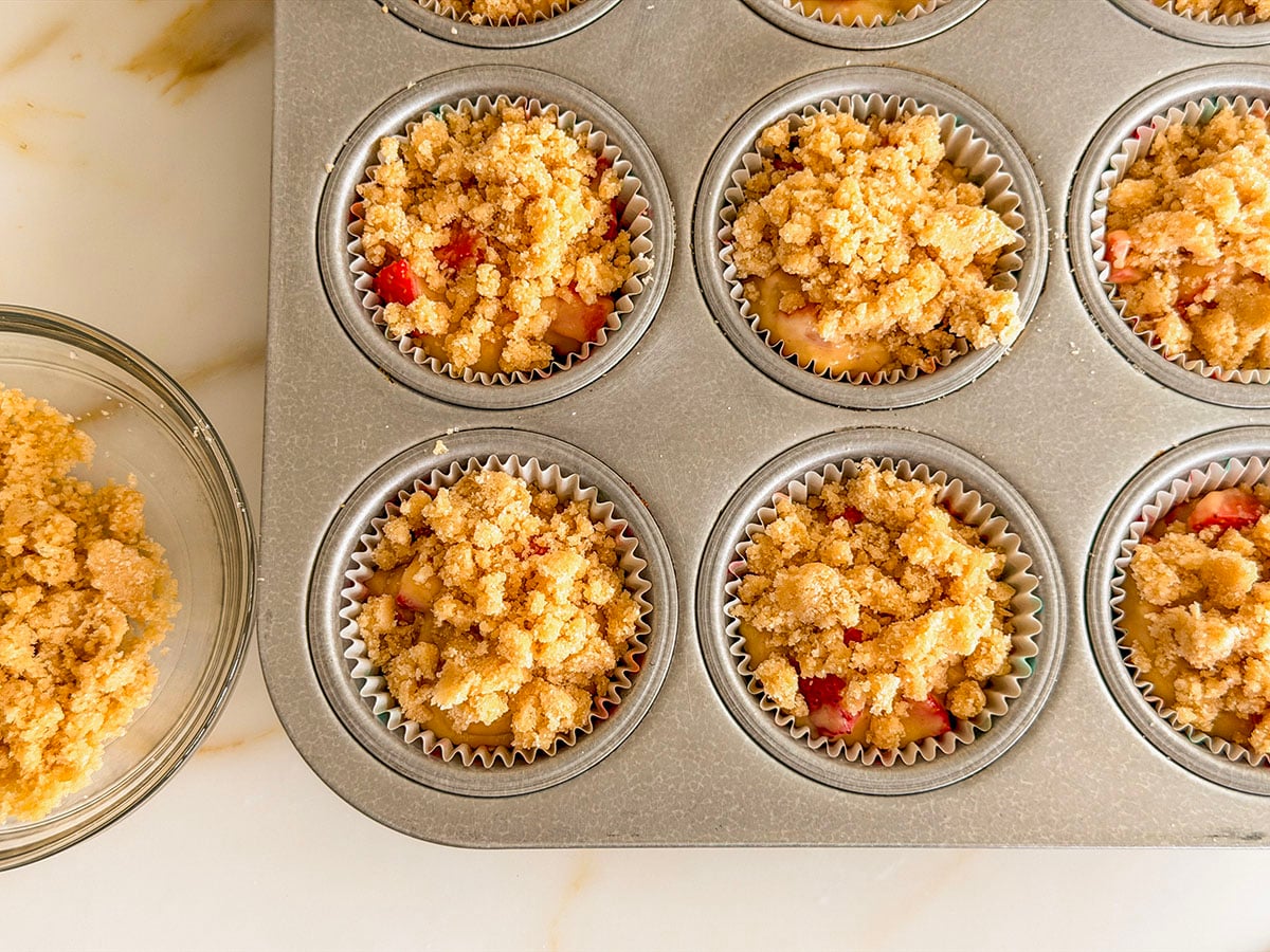 Crumb topping divided on top of batter for muffins in a muffin tin