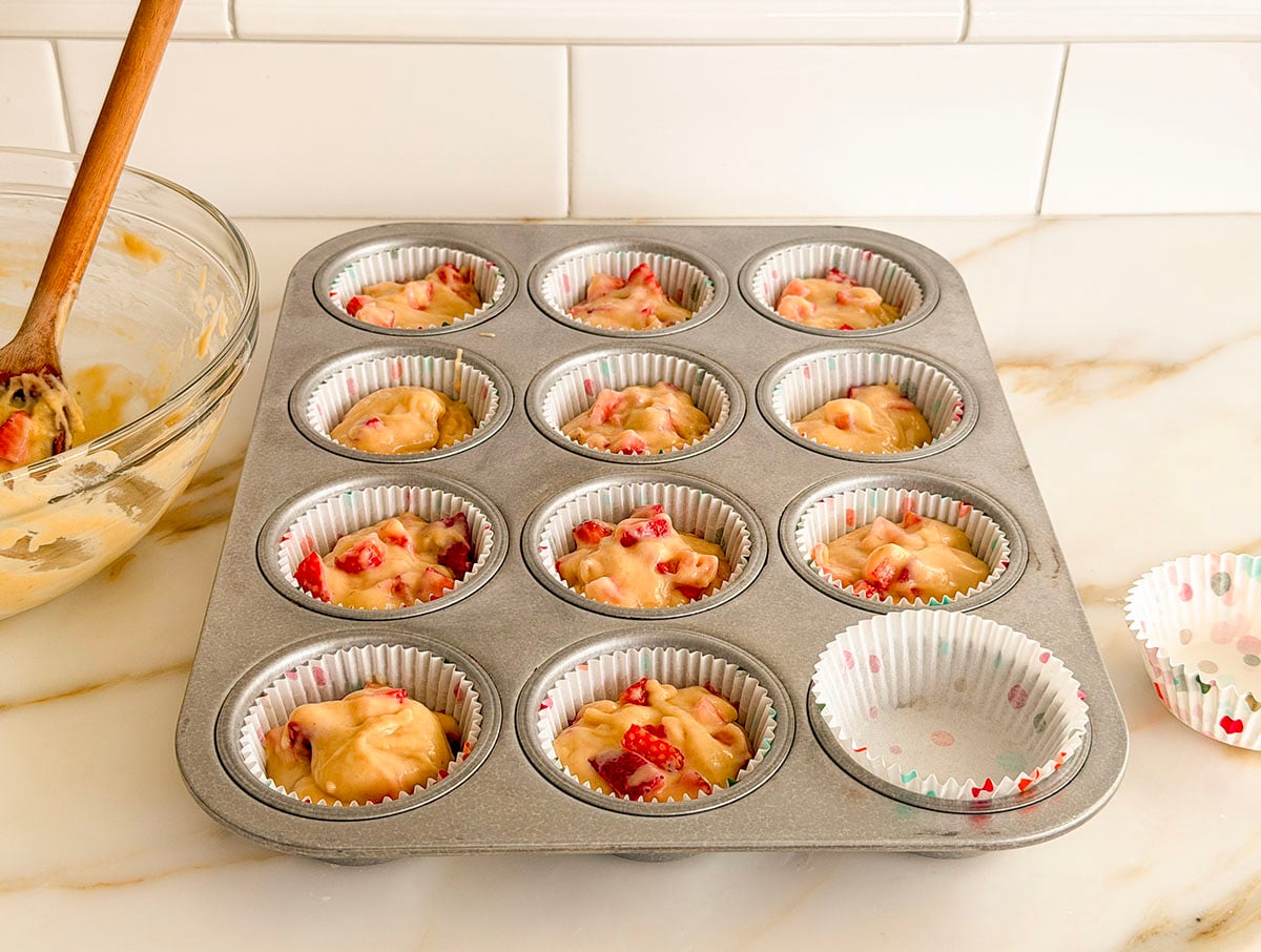 Strawberry muffin batter divided into a muffin tin for 12 muffins