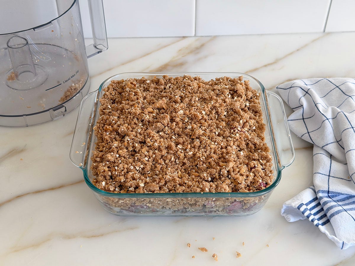 Unbaked rhubarb crisp with topping in a glass baking dish