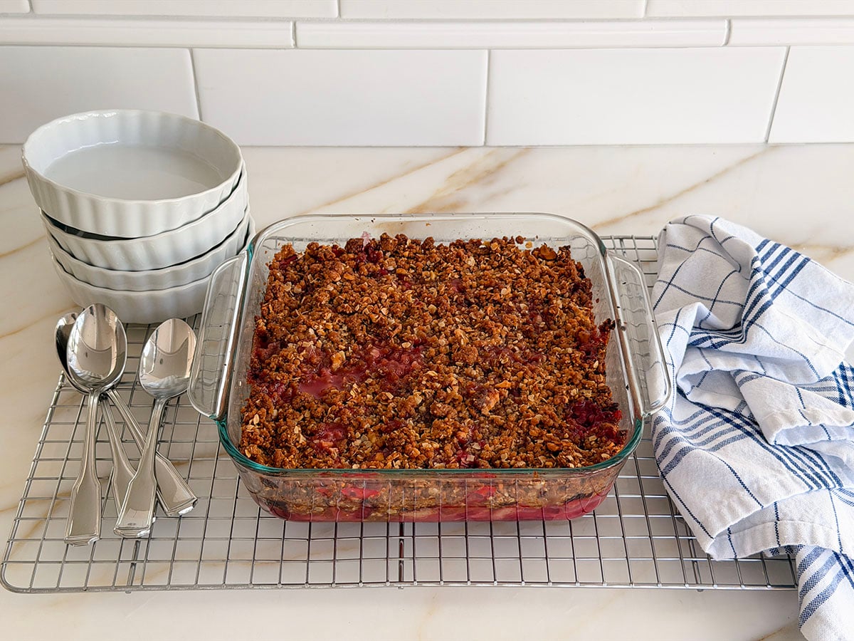 Baked rhubarb crisp in a glass baking dish on a cooling rack