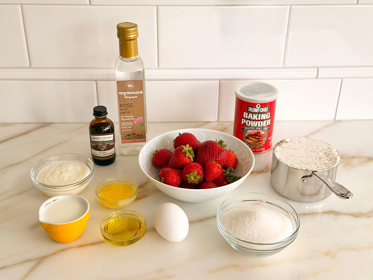 Ingredients for strawberry muffins on a marble countertop