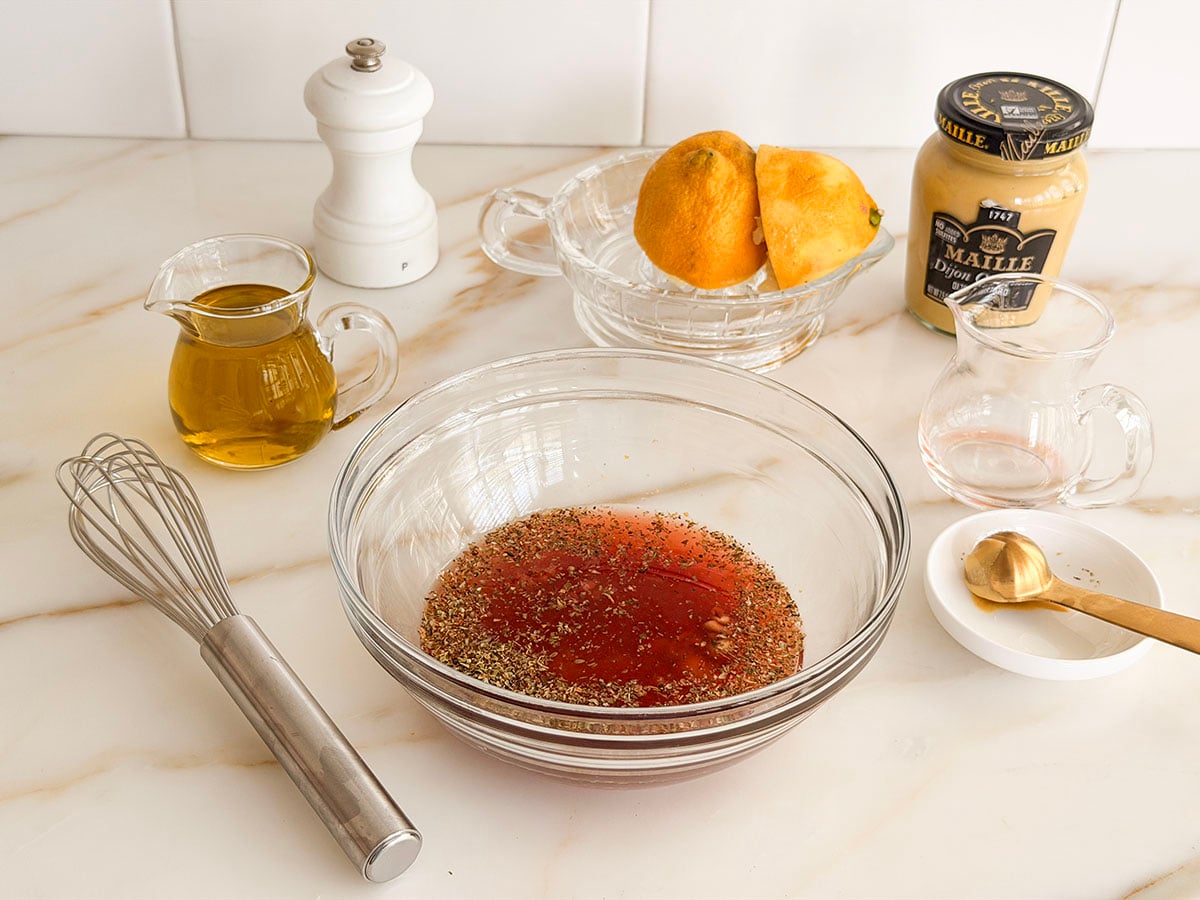 Greek Salad dressing ingredients and whisk with glass bowl and jars