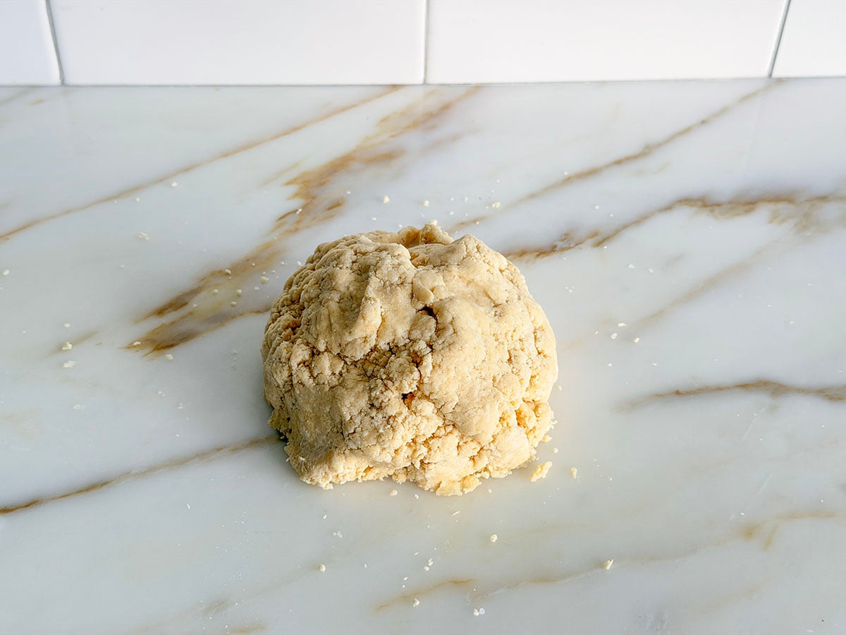 Pie dough in a ball on a marble countertop