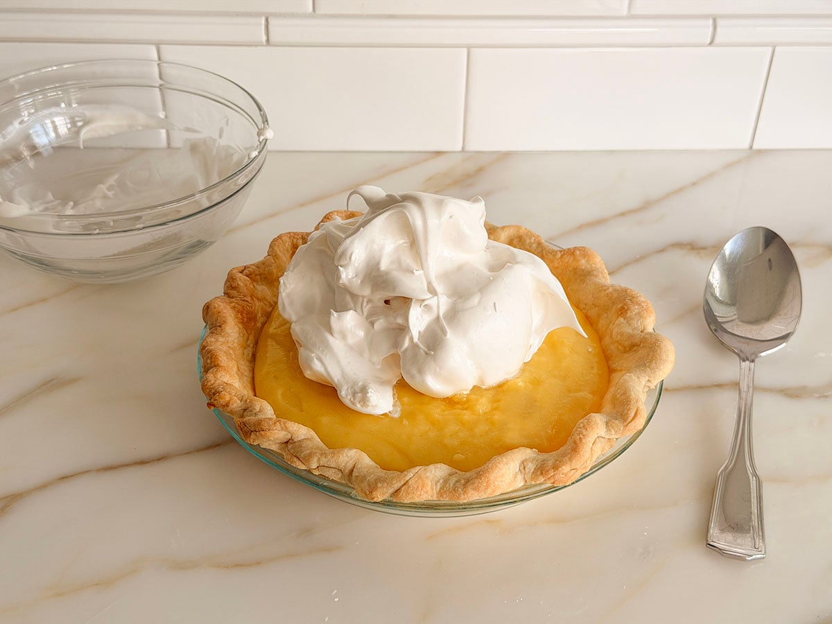 Lemon pie filling with a dollop of meringue on top and a spoon on the side