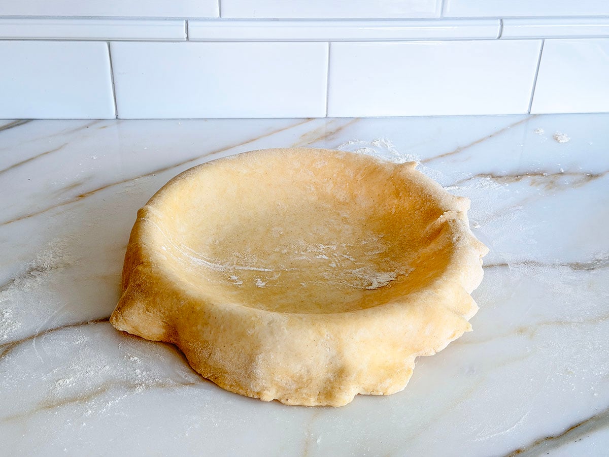 Rolled butter pie crust dough draped over a pie plate