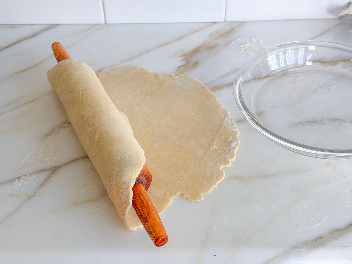 Rolled pie dough wrapped over a wood rolling pin