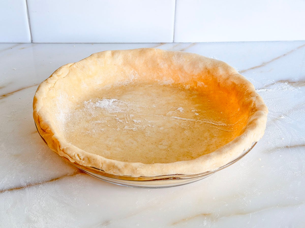 Butter pie crust in a pie plate ready to crimp the edges