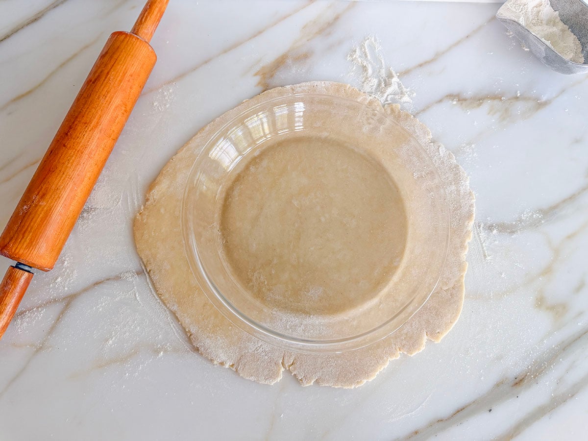 Rolled pie dough with glass pie plate on top