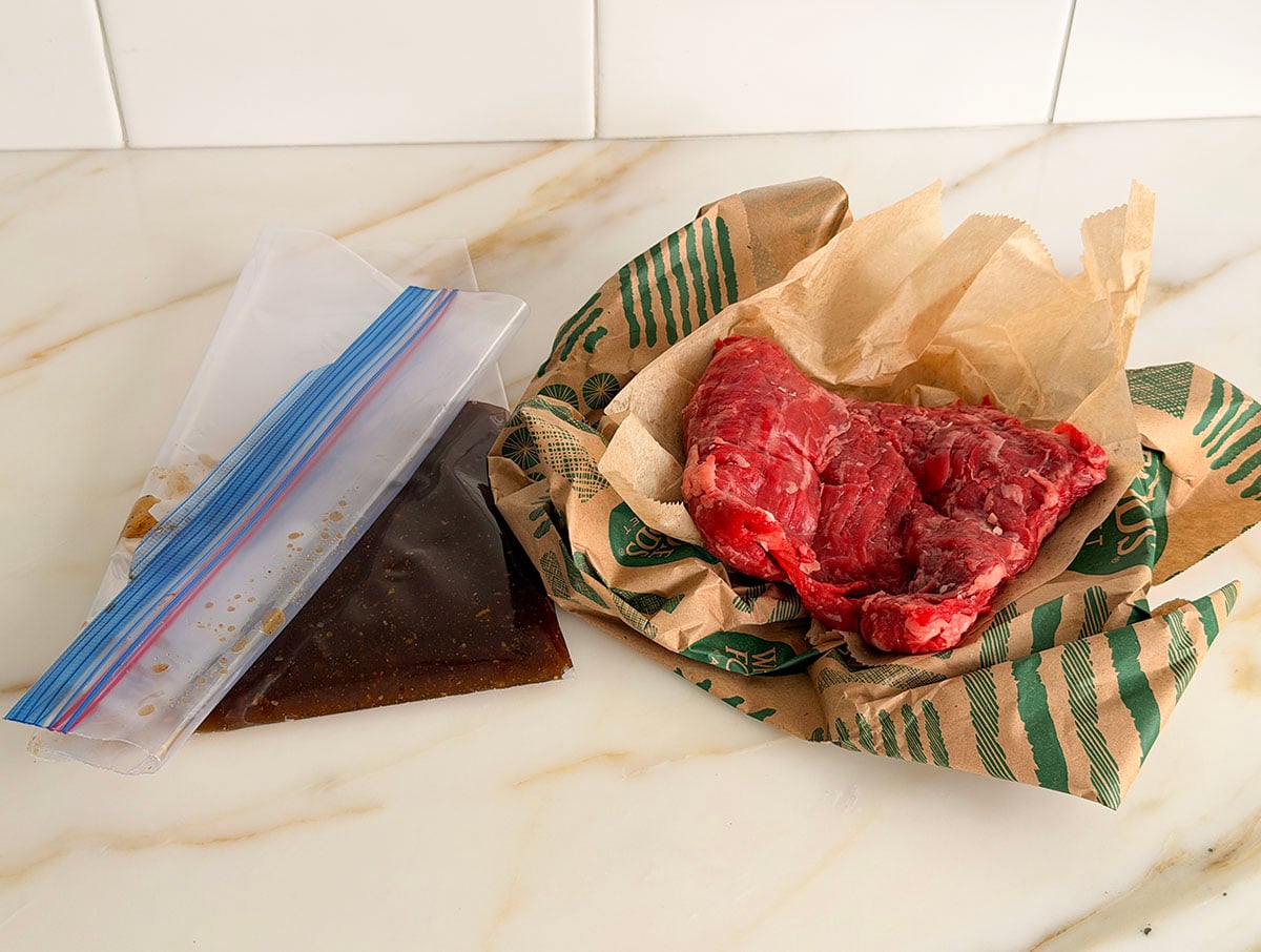 Marinade for steak in a plastic bag with steak on the side
